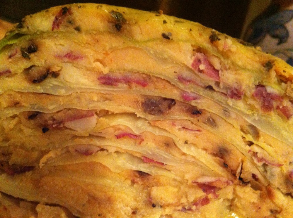 A wedge of the stuffed cabbage, showing the layers of smoked cheddar mashed potatoes and cabbage leaves